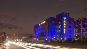 Ein Hotel mit einem gut sichtbaren 'HOTEL'-Schild, mehreren Etagen und einem modernen Design.
