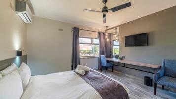 A hotel room with a bed, a desk, a chair, a TV, and a ceiling fan.