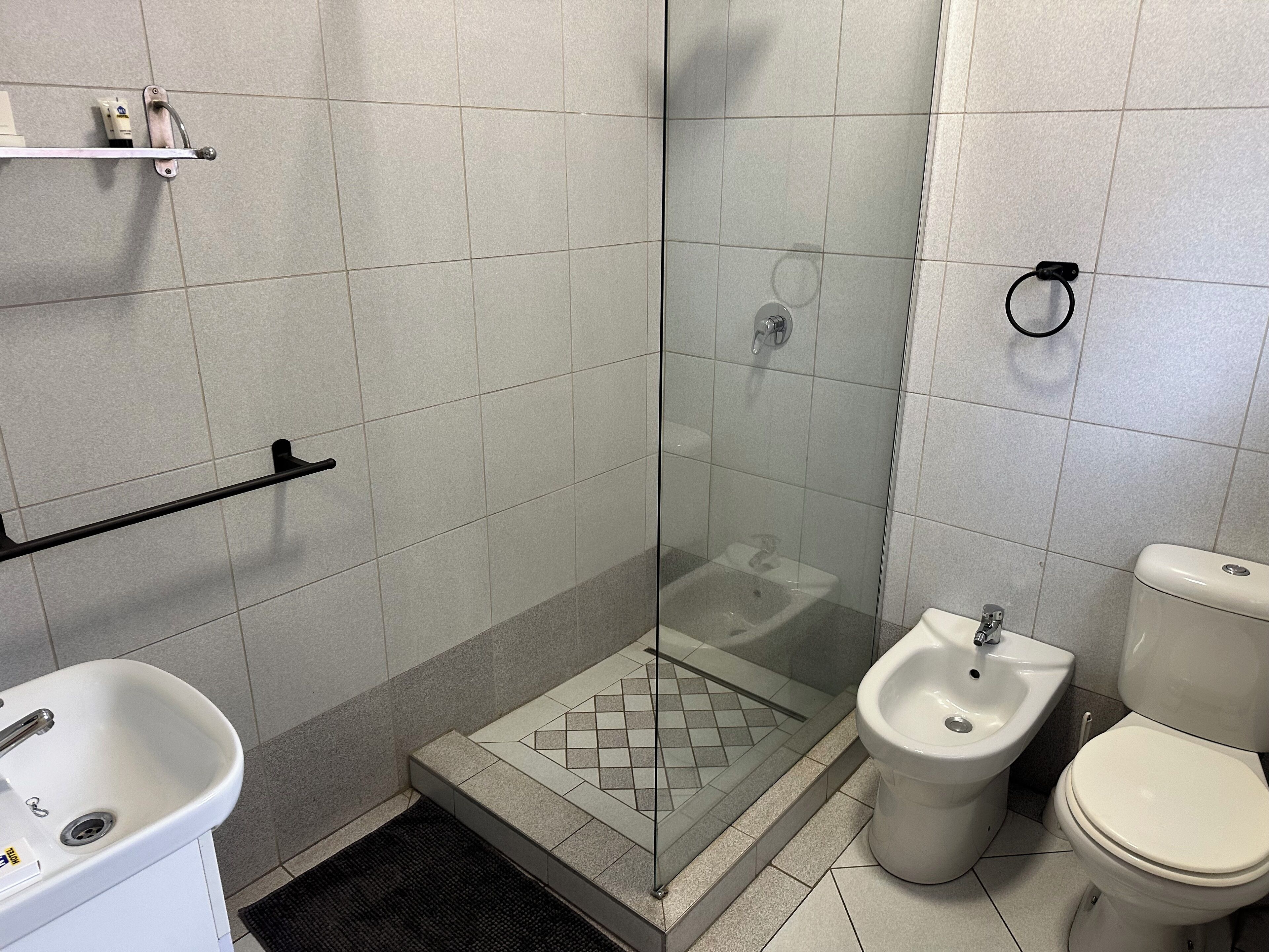 A bathroom with a glass-enclosed shower, a bidet, and a toilet.
