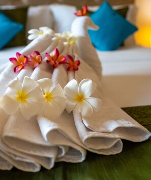 A neatly folded towel with white and yellow flowers on a green surface. - Justa Casa Frangipani Assagao, Goa (Assagao)