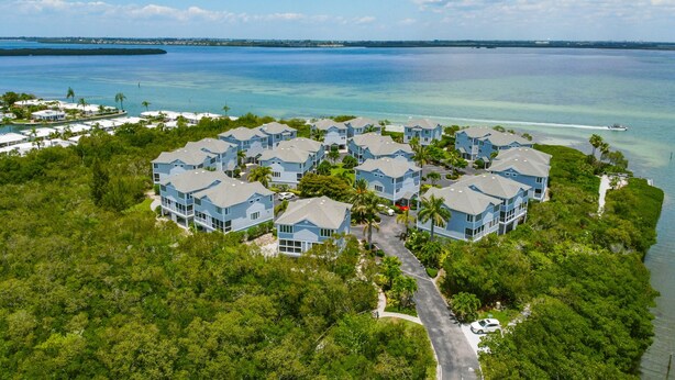 Un resort con varias edificaciones azules rodeado de exuberante vegetación y una vista despejada del océano.