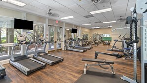 Un gimnasio con cintas de correr, máquinas de pesas y colchonetas de ejercicio.