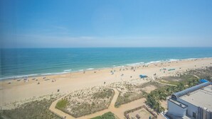 A beach with a clear sky, sandy shore, and a few umbrellas.