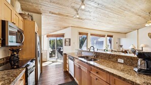 A kitchen with wooden cabinets, granite countertops, and a large window providing a view of the outdoors. - Snowflake Lookout: Ski In/Out Breckenridge Townhome with Hot Tub (Breckenridge)