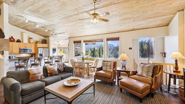 A spacious living room with a wooden ceiling, a dining area, and large windows offering mountain views. - Snowflake Lookout: Ski In/Out Breckenridge Townhome with Hot Tub (Breckenridge)
