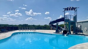 Ein Schwimmbecken mit Wasserrutsche, Liegestühlen und einem Rettungsschwimmturm.