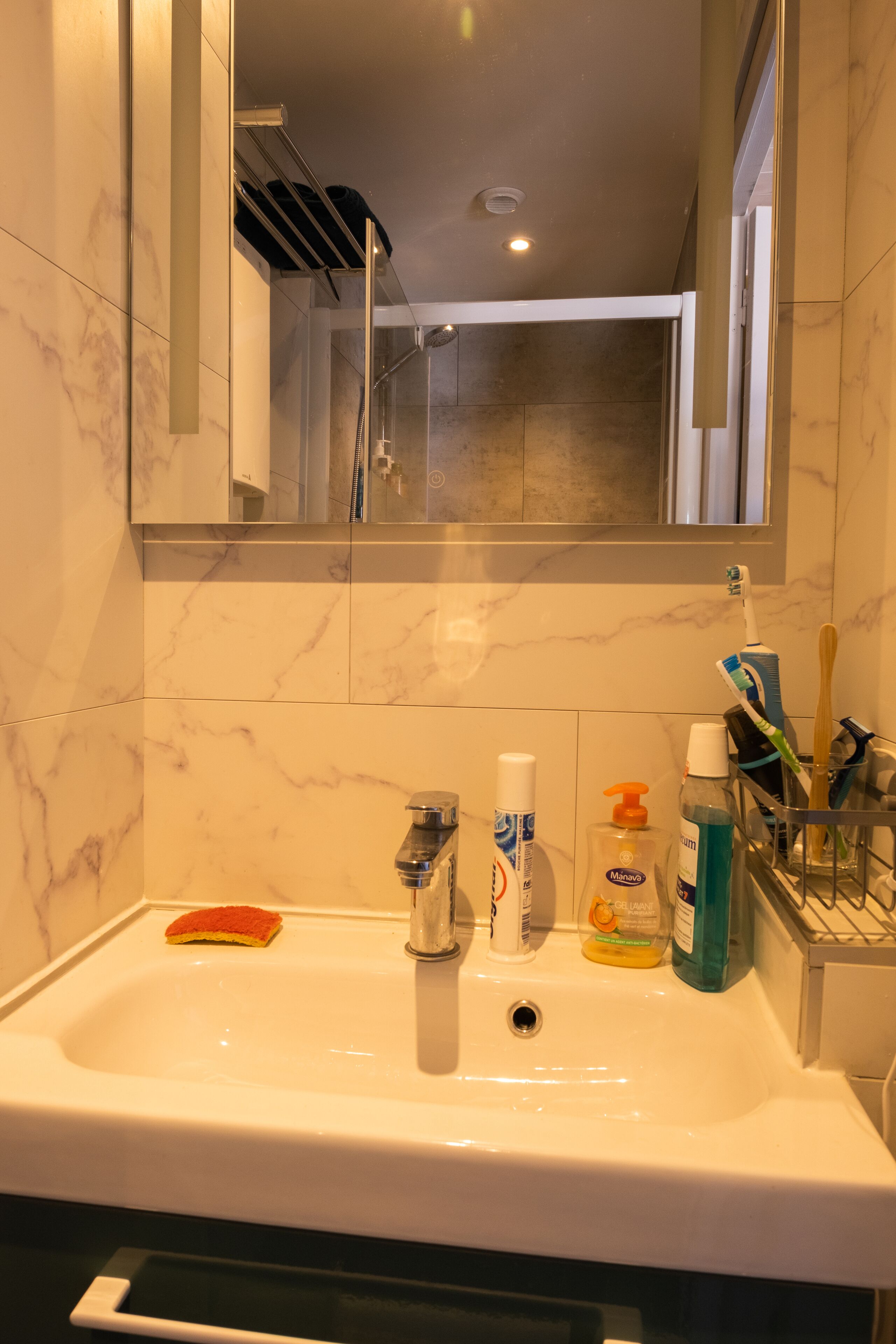A bathroom with a white sink, a mirror, and toiletries.