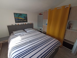 Un dormitorio con una cama, una mesita de noche, un armario y un cuadro en la pared.