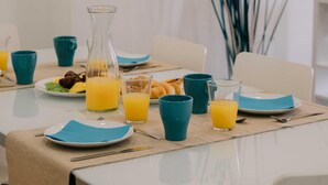 Una mesa de desayuno con platos, vasos y una botella de jugo de naranja.
