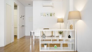 Una habitación moderna y bien iluminada con una consola blanca, sillas y una lámpara de pie.