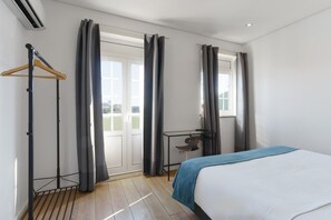 A hotel room with a bed, a desk, and a window with curtains.