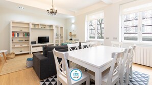 Un salon moderne comprenant un coin repas, un téléviseur et un lustre.
