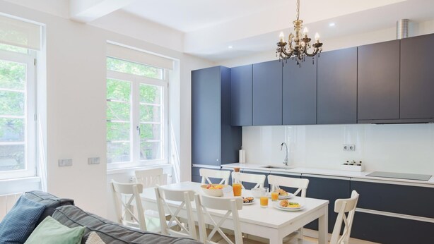 A modern kitchen with dark cabinets, a white countertop, and a chandelier. - Feel Porto Downtown Essence (Porto)