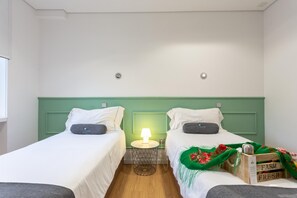 Habitación doble con dos camas, una mesita de noche con lámpara y una pequeña mesa.