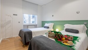 A room with two beds, a window, a radiator, and a breakfast setup on the bed. - Feel Porto Downtown Essence (Porto)