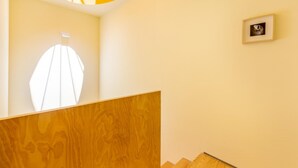 A staircase with wooden steps and a wooden handrail, leading to a landing with a framed picture on the wall. - Feel Porto Code al Apartment 0 1 (Porto)