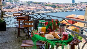 A balcony with a table set for breakfast, overlooking a cityscape and waterfront. - Feel Porto Code al Apartment 0 1 (Porto)