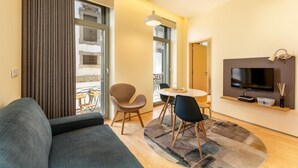 A modern living room with a sofa, dining table, chairs, and a TV. - Feel Porto Code al Apartment 0 1 (Porto)