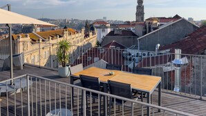 A rooftop terrace with a table and chairs, a potted plant, and a view of the cityscape including a prominent tower. - Galerias Cashmere Nightlife 302 by Feel Porto (Porto)