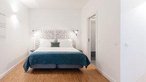 A bedroom with a bed, white walls, a patterned headboard, and a wooden floor. - Galerias Cashmere Nightlife 302 by Feel Porto (Porto)