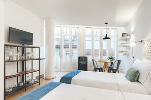 Hotelkamer met twee bedden, een televisie, een kitchenette en een balkon met uitzicht.