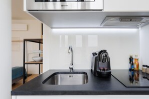 Een moderne keuken met een roestvrijstalen spoelbak, een koffiezetapparaat en een afzuigkap.
