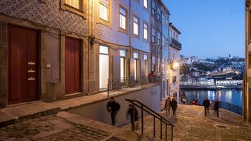 A historic building with a cobblestone staircase leading to a balcony overlooking a river.