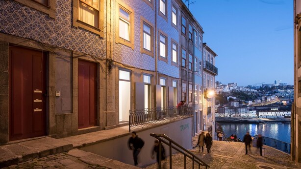 A historic building with a stone facade, multiple windows, and a staircase leading to a balcony overlooking a waterfront. - Feel Porto Code al Studio 1 2 (Porto)