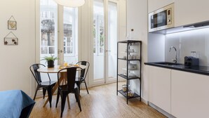 A modern kitchen with a dining area, a microwave, and a shelf with dishes. - Galerias Cotton Cozy Nightlife 101 by Feel Porto (Porto)
