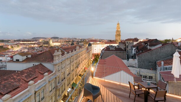 Una terraza en la azotea con vistas a un paisaje urbano, incluyendo una torre destacada.
