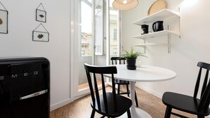 Et moderne køkken med en hvid bordplade, sorte stole, et rundt bord og en hængende lampe.