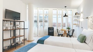 Et hotelværelse med to senge, et fjernsyn, et tekøkken og en balkon med udsigt.