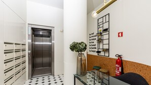 En moderne elevator, en brandslukker, et glasbord med en plante og et motiverende citat på væggen.