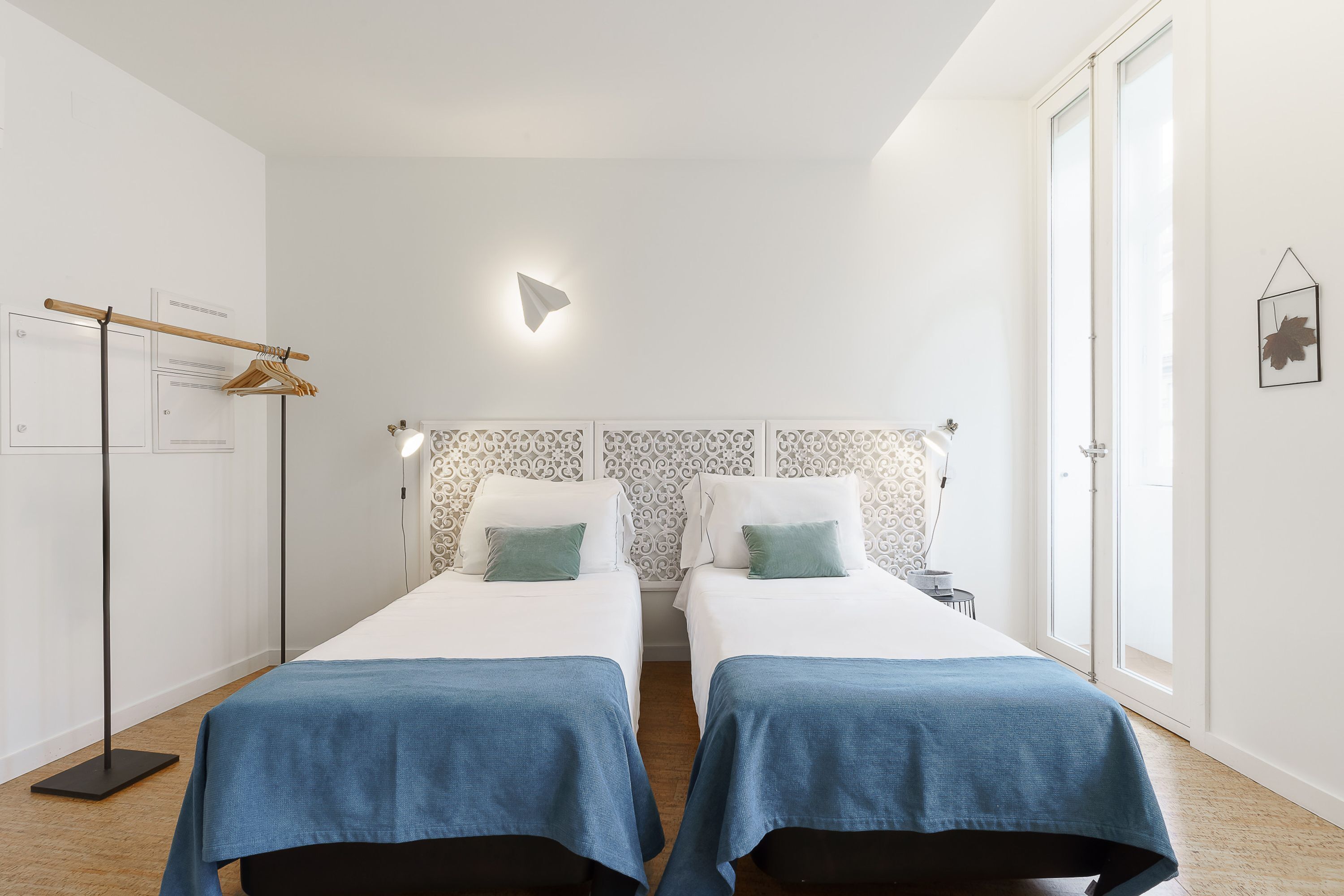 Hotellihuone, jossa on kaksi sänkyä, vaatekaappi, peili ja ikkuna.