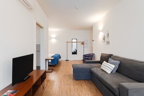 A modern living room with a flat-screen TV, a sofa, a coffee table, and a small table with a blue tablecloth. - Galerias On Trend Nightlife 203 by Feel Porto (Porto)