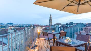 A rooftop terrace with a table, chairs, and an umbrella.
