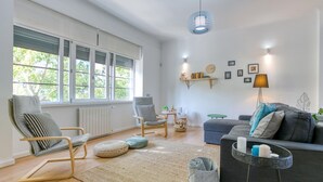 Una sala de estar moderna con un sofá, sillas, una mesa de centro y un ventanal grande.