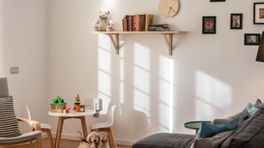 Un salón acogedor con una estantería de madera, un osito de peluche y una mesita llena de juguetes.