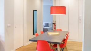 A modern dining area with a rectangular table, red chairs, and a red pendant light. - Feel Porto Downtown Harmony (Porto)