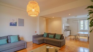 A modern living room with a sectional sofa, a glass coffee table, and a hanging light fixture. - Feel Porto Downtown City Break (Porto)