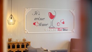A living room with a wall-mounted sign that reads "It's wine time" and "OPORTO Red Wine".