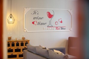 A living room with a wall-mounted sign that reads "It's wine time" and "OPORTO Red Wine". - Feel Porto Ruby Townhouse (Porto)