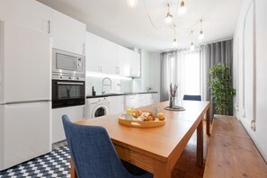 A modern kitchen with white cabinets, a wooden dining table, and a breakfast tray.