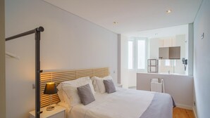 Un dormitorio moderno con cama, mesita de noche, lámpara y un espejo grande.