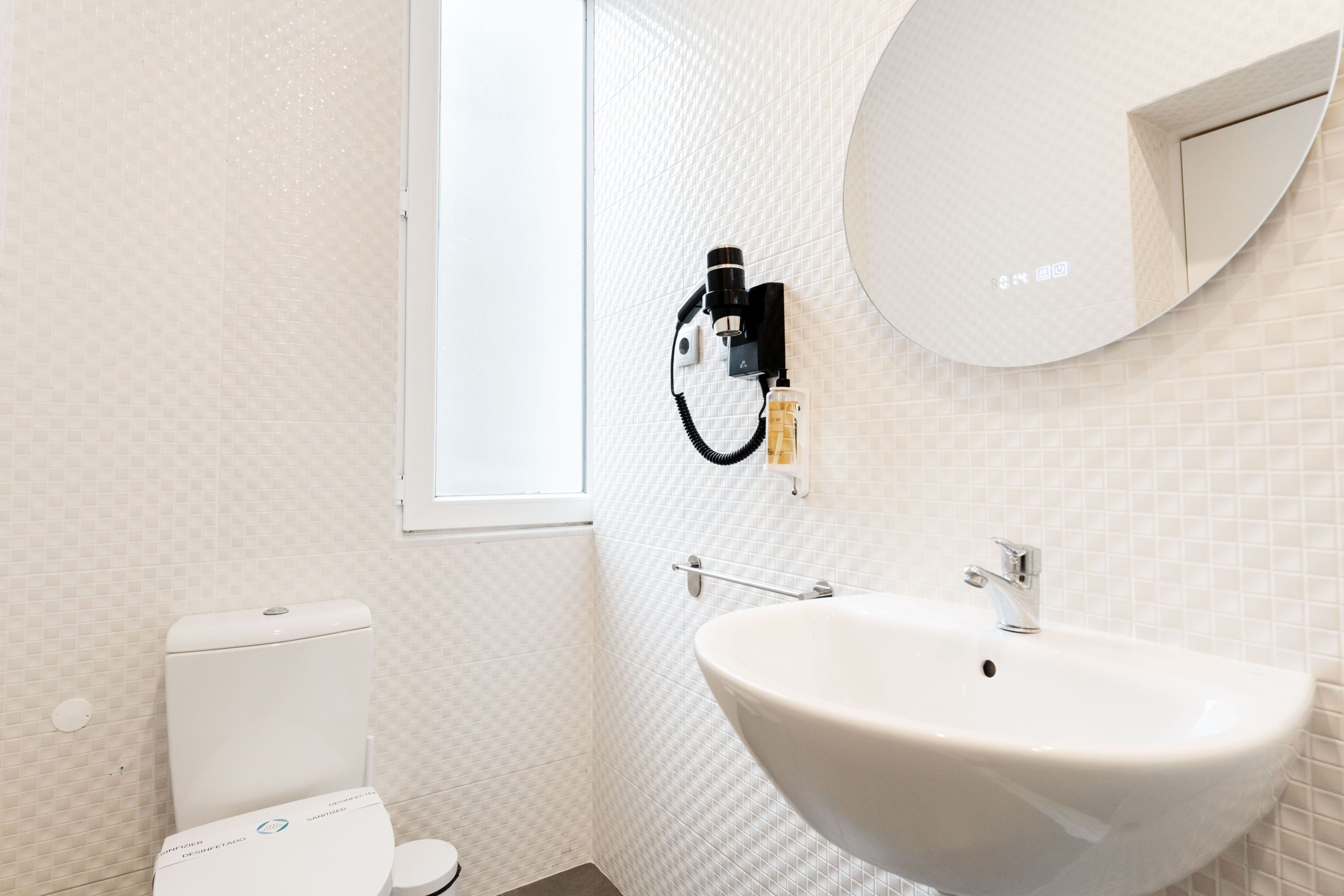 A bathroom with a toilet, a sink, and a mirror.