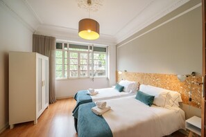 A hotel room with two beds, a wardrobe, a large window, and a corkboard wall. - Feel Porto Downtown Luxury Retreat (Porto)