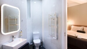 Ein modernes Badezimmer mit Waschbecken, Spiegel, Toilette und Handtuchhalter.