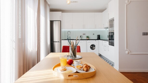 A modern kitchen with a wooden table, breakfast tray, and a view of the living area. - Feel Porto DOC Townhouse (Porto)