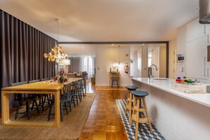A modern kitchen with a wooden dining table, bar stools, and a white countertop.