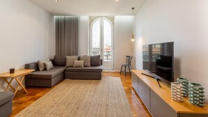 Ein modernes Wohnzimmer mit einer Eckcouch, einem Fernseher und einem Holztisch.